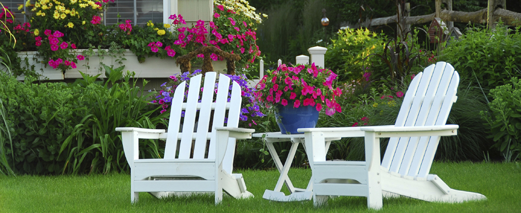 Two lawn chairs in a beautiful garden with colourful flowers