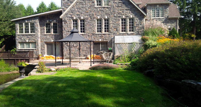 backyard of grey luxury residential home with pergola and freshly cut lawn